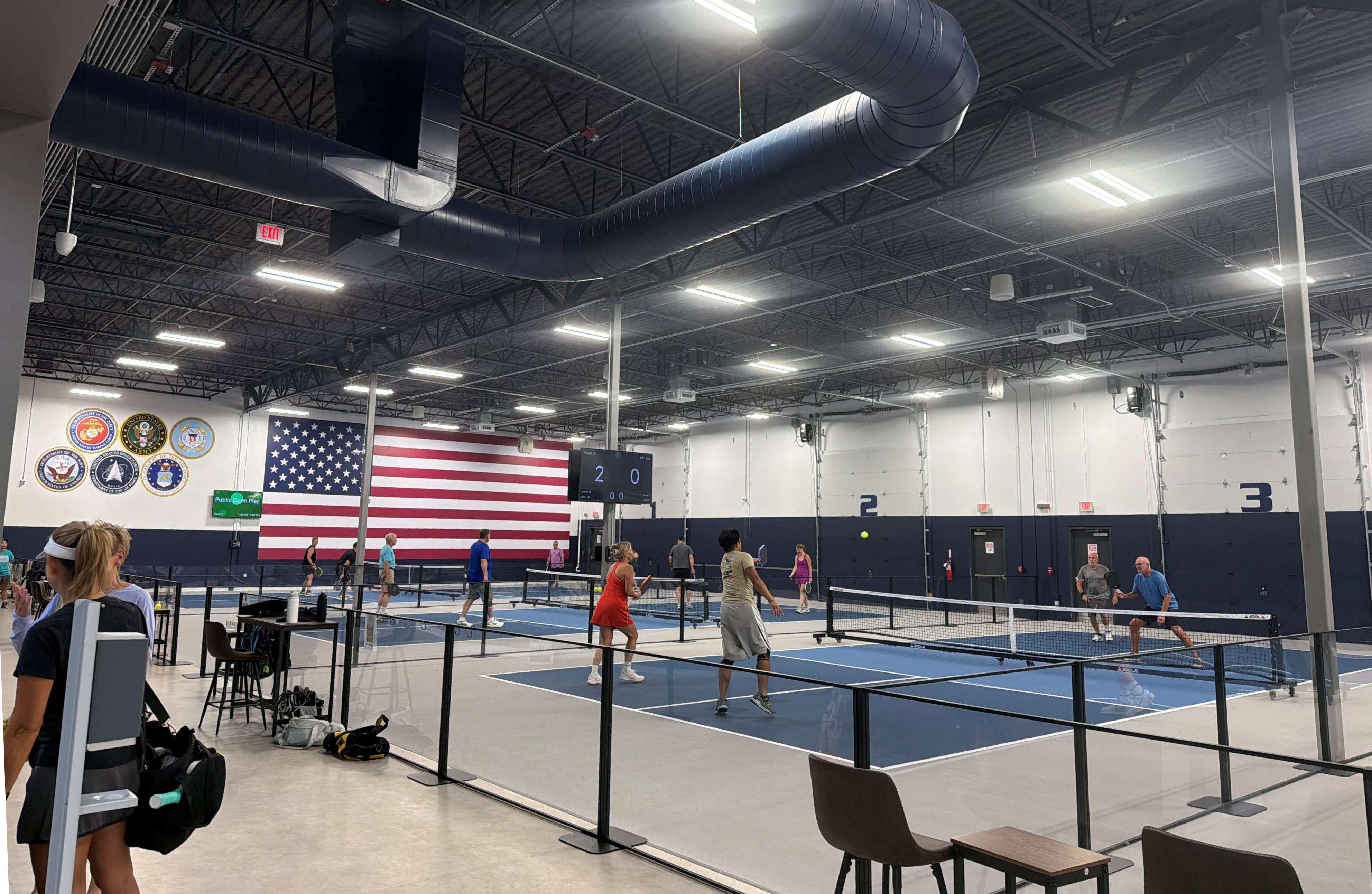 Players on the courts at The Pickl Park with the American flag mural